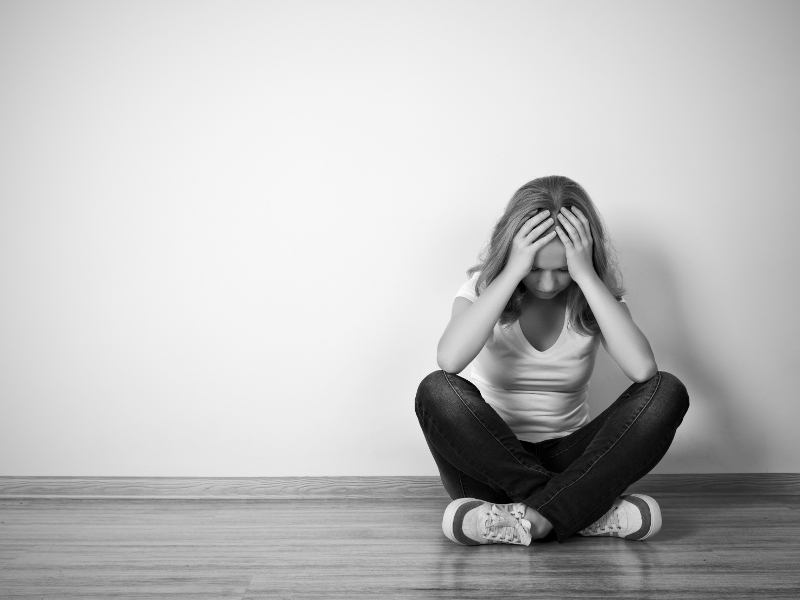 girl sits in a depression on the floor near the wall monochrome