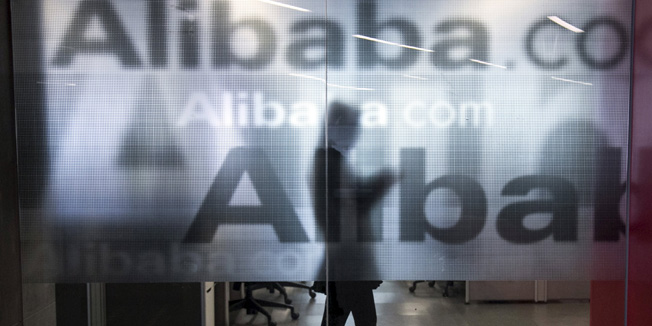 An employee is seen behind a glass wall with the logo of Alibaba at the company's headquarters on the outskirts of Hangzhou, Zhejiang province, in this April 23, 2014 file photo. Hackers in China attempted to access over 20 million active accounts on Alibaba Group Holding Ltd's Taobao e-commerce website using Alibaba's own cloud computing service, according to a state media report posted on the Internet regulator's website. REUTERS/Chance Chan/Files