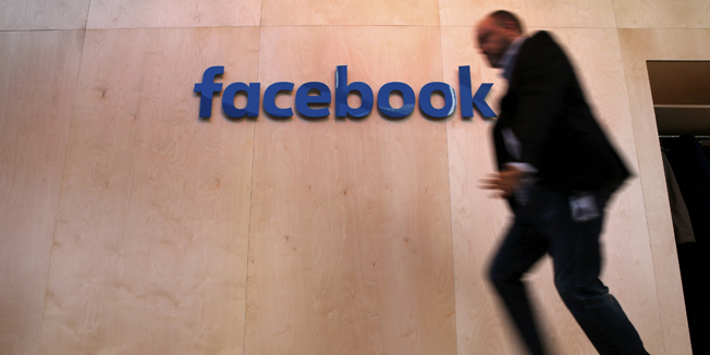A man walks in front of the Facebook logo at the new Facebook Innovation Hub during a preview media tour in Berlin, Germany, February 24, 2016.      REUTERS/Fabrizio Bensch