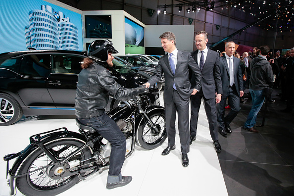 Harald Krueger, chief executive officer of Bayerische Motoren Werke AG (BMW), centre, shakes hands with the rider of a vintage BMW motorcycle at a news conference on the first day of the 86th Geneva International Motor Show in Geneva, Switzerland on Tuesday, Mar. 1, 2016. The show opens to the public on Mar. 3, and will showcase the latest models from the world's top automakers. Photographer: Jason Alden/Bloomberg via Getty Images 