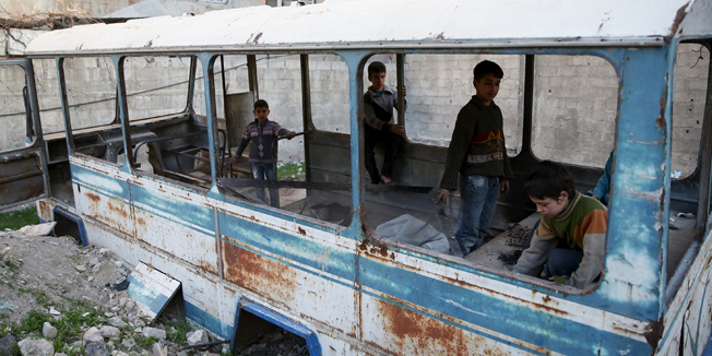 Children play in a damaged school bus in the rebel held besieged town of Jesreen, in the eastern Damascus suburb of Ghouta, Syria March 7, 2016. REUTERS/Bassam Khabieh