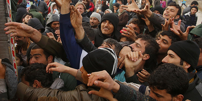 Migrants try to get products from a truck at a makeshift camp on the Greek-Macedonian border near the village of Idomeni, Greece March 10, 2016. REUTERS/Stoyan Nenov
