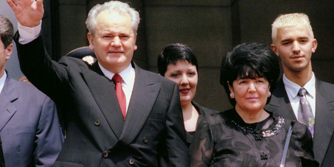 Slobodan Milosevic (L) waves to supporters after being sworn in as Yugoslav President outside Yugoslav parliament in Belgrade July 23. With him are (L to R), his daughter Marija, wife Mira Markovic, also his coalition partner, and his son Marko. - RTXHE2V