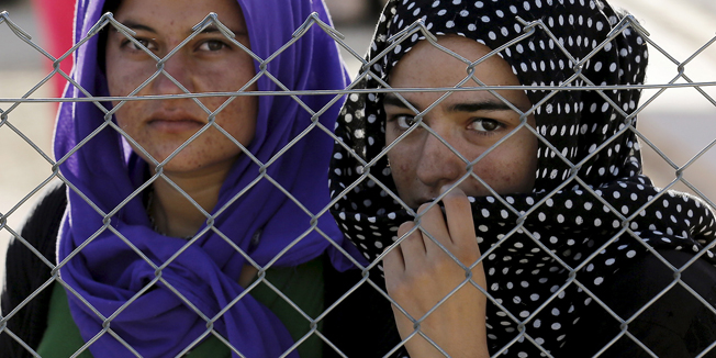 Yazidi refugees stand behind fences as they wait for the arrival of United Nations High Commissioner for Refugees Special Envoy Angelina Jolie at a Syrian and Iraqi refugee camp in the southern Turkish town of Midyat in Mardin province, Turkey, June 20, 2015. REUTERS/Umit Bektas      TPX IMAGES OF THE DAY      - RTX1HEPQ