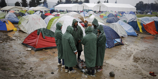 Migrants warm themselves by a fire at a makeshift camp on the Greek-Macedonian border, near the village of Idomeni, Greece March 10, 2016. REUTERS/Stoyan Nenov