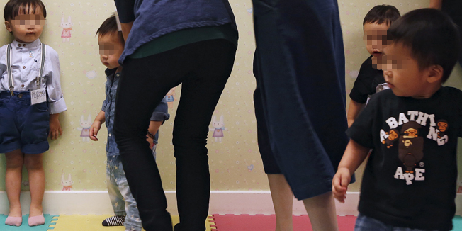 A teacher (L) and mothers try to teach kids to stand at attention during a specialized class preparing toddlers for kindergarten interviews in Hong Kong, China May 17, 2015. Parents believe that getting a place in a good kindergarten will help them secure a spot in a good primary and secondary school and pave the way for a good start in life. With the competition being so fierce, sought-after kindergartens can be selective about who they let in. Pre-kindergarten interview courses train them to be disciplined, responsive and polite through games, music and dance. They also offer one-on-one mock interview sessions. Picture taken May 17, 2015.  REUTERS/Bobby Yip - RTX1E7OA