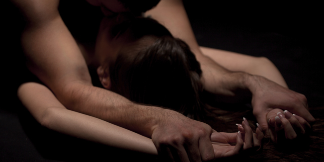 Yping cople have a sex with passion. Man is lying over woman and holding her hands.