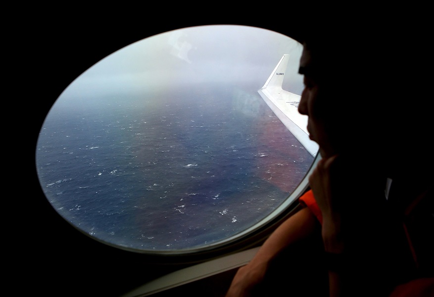 Crew member Koji Kubota of the Japan Coast Guard looks out an observation window aboard the Japan Coast Guard Gulfstream V aircraft as it flies over the southern Indian Ocean looking for debris from missing Malaysian Airlines flight MH370 April 1, 2014. The last words from the cockpit of a missing Malaysian jet were a standard 