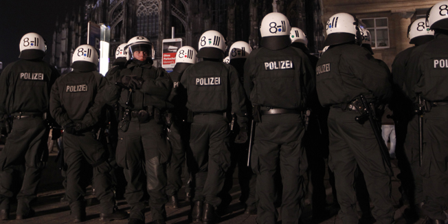 An anti-racism poster is displayed in a window of a building as police stand guard in front of Cologne Cathedral during a demonstration march by members of KOGIDA, the Cologne arm of the anti-immigrant movement Patriotic Europeans Against the Islamisation of the West (PEGIDA) January 21, 2015. The weekly PEGIDA demonstrations began last October as a local protest against the building of new shelters for refugees, and have been growing in size. Counter-marches have taken place across Germany, with far larger numbers, and German Chancellor Angela Merkel has condemned the group in unusually strong language as racists 