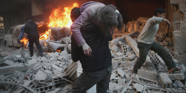 ATTENTION EDITORS - VISUAL COVERAGE OF SCENES OF INJURYA man carries an injured child amidst rubble near a burning vehicle in a site damaged from what activists said was shelling by forces loyal to Syria's President Bashar al-Assad in the town of Douma, eastern Ghouta in Damascus, Syria December 30, 2015. REUTERS/Bassam Khabieh - RTX20JNX