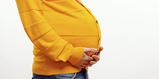 What if men could bear children. Funny conceptual photo of gender reversal when a pregnant man with a belly smiling at camera while posing isolated on white background