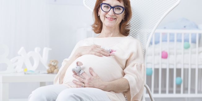 Older happy woman in pregnant resting on armchair