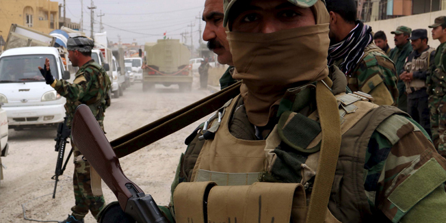 Volunteers from the Yazidi sect who have joined the Kurdish peshmerga forces stand during Yazidi people loot houses the town of Sinjar, Iraq November 16, 2015. Before it was overrun by Islamic State, Sinjar and the surrounding villages were home to about 200,000 people, mainly Kurdish and Arab Muslims - both Sunni and Shi'ite - as well as Christians and Yazidis, a faith that combines elements of several ancient Middle Eastern religions. Now the town is largely deserted. But in a row of houses used by Islamic State fighters, there were signs of recent occupation: a smell of rotting food, and foam mattresses and pillows laid on the floor. Picture taken November 16 2015. REUTERS/Azad Lashkari      TPX IMAGES OF THE DAY      - RTS7Y63
