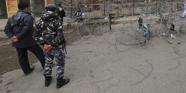 A policeman oversees workers removing barbed wire that was erected last year when the country was hit by a series of protests against the government, ignited by a dispute over uncollected rubbish, in front of the government palace in Beirut, Lebanon January 6, 2016. Lebanon's cabinet agreed on December 21, 2015 to export the country's waste in a move that could end a crisis that led to a wave of protests and threatened the downfall of the government. REUTERS/Aziz Taher - RTX218MY