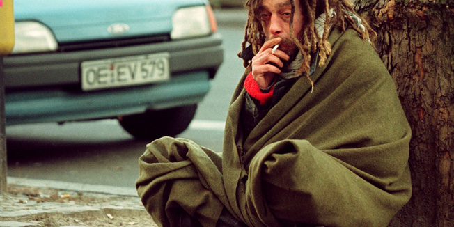 A homless man smokes a cigarette as he sits next to a tree begging for alms at Berlin's famous Kurfuerstendamm Boulevard December 16. Temperatures in the German capital are expected to fall to -14 degrees centigrade tonight, the coldest night in December of this year.WEATHER - RTR9N5C