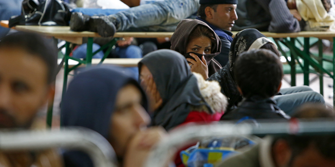 A woman covers her face as migrants rest at a registration centre in Passau, Germany October 8, 2015. REUTERS/Michaela Rehle - RTS3KLH