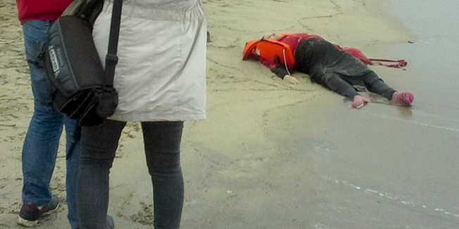 ATTENTION EDITORS - VISUAL COVERAGE OF SCENES OF DEATH AND INJURY People take pictures as the body of a migrant lies on the shore in the Aegean coastal town of Ayvalik, Turkey January 5, 2016.Turkish authorities said they found the bodies of 27 migrants, at least three of them children, at two separate locations on the Aegean coast on Tuesday after a migrant boat apparently capsized as it tried to reach the Greek island of Lesbos.  REUTERS/Cihan News Agency NO RESALES. NO ARCHIVES. FOR EDITORIAL USE ONLY. NOT FOR SALE FOR MARKETING OR ADVERTISING CAMPAIGNS. TEMPLATE OUT. TURKEY OUT. NO COMMERCIAL OR EDITORIAL SALES IN TURKEY.  TEMPLATE OUT