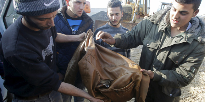 People check the jacket of a Palestinian, whom Palestinian officials said was killed by Israeli soldiers, near the scene where Israeli military said another Palestinian tried to stab a soldier, in the West Bank city of Hebron January 12, 2016. An Israeli military spokeswoman said troops fatally shot a Palestinian who tried to stab a soldier in the West Bank city of Hebron. Palestinian officials gave his age as 17 and said another Palestinian was killed by Israeli soldiers in the city. The Israeli military had no immediate information about a second fatality in Hebron. REUTERS/Mussa Qawasma  