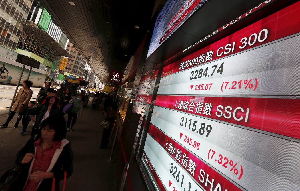 People walk past a panel displaying China stock market indexes, which were down more than seven percent and were suspended for the rest of the day, for the second time this week, in Hong Kong, China January 7, 2016. REUTERS/Bobby Yip