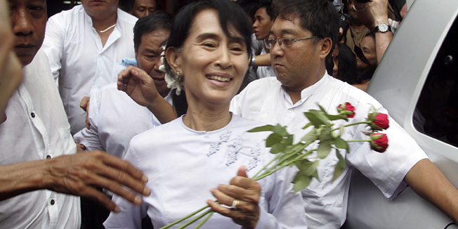 Myanmar pro-democracy leader Aung San Suu Kyi receives flowers from supporters as she leaves the headquarters of her National League for Democracy party in Yangon, Myanmar Monday, April 2, 2012. Suu Kyi claimed victory Monday in Myanmar's historic by-election, saying she hoped it will mark the beginning of a new era for the long-repressed country. (AP Photo/Khin Maung Win)