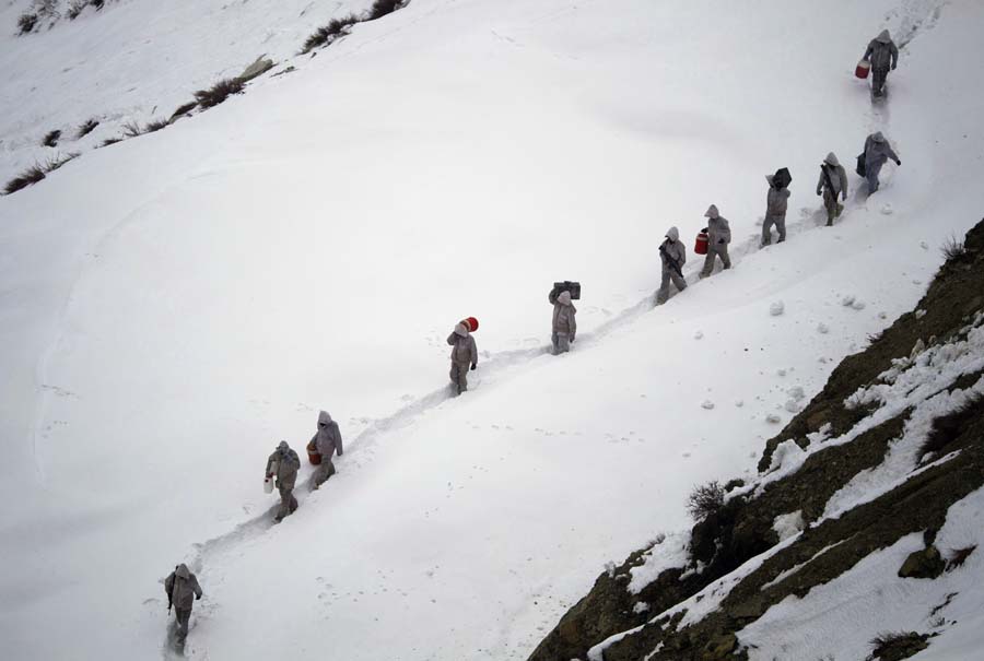 FILE - In this Feb. 19, 2012 file photo, Pakistani Army soldiers with the 20th Lancers Armored Regiment, carry supplies up the 2,400 meter (8,000-foot) mountain near their outpost, Kalpani Base, in Pakistan's Dir district. An avalanche smashed into a Pakistani army base on a Himalayan glacier close to India on Saturday, April 7, 2012, burying around 130 soldiers. (AP Photo/Anja Niedringhaus, File)