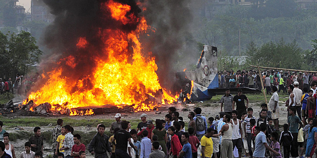 FOR USE AS DESIRED, YEAR END PHOTOS - FILE - In this Sept. 28, 2012 file photo, Nepalese gather around the burning wreckage at the crash site of a Sita Air airplane near Katmandu, Nepal. The plane carrying trekkers to the Everest region crashed and burned just after takeoff in NepalÌs capital, killing the 19 Nepali, British and Chinese people on board. (AP Photo/File)