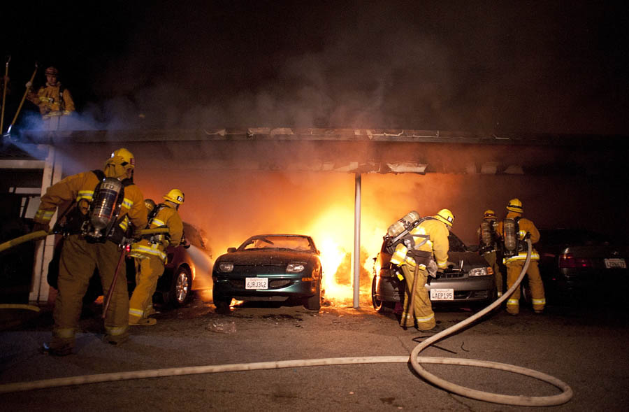 Los Angeles Fire Department firefighters extinguishes numerous cars on fire in a carport in the Sherman Oaks neighborhood of Los Angeles on Monday, Jan. 2, 2012. For the fifth night in a row, a spate of arson fires has sent firefighters scrambling to extinguish car fires in the Hollywood, Hollywood Hills, Studio City, and Sherman Oaks neighborhoods of Los Angeles. The Los Angeles Fire Department confirms a person of interest has been detained and is being questioned in connection with the arson spree. (AP Photo/Dan Steinberg)