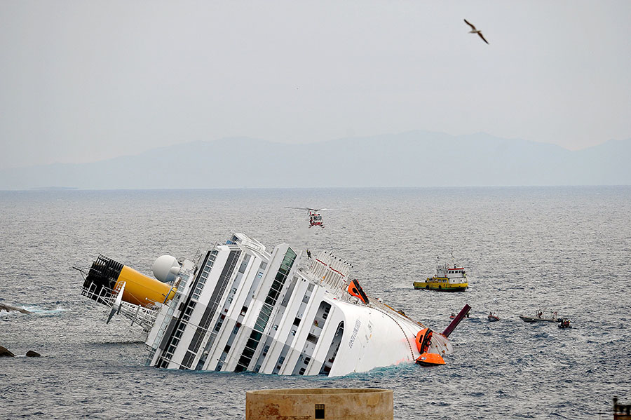 A rescue boat and an helicopter patrol near the Costa Concordia cruiseship, on January 16, 2012 outdoor of the harbor of the Tuscan island of Giglio after it ran aground and keeled over off the Isola del Giglio after hitting underwater rocks on January 13. The owner of the luxury liner that ran aground off the coast of Italy, killing at least six people, said its captain had made 