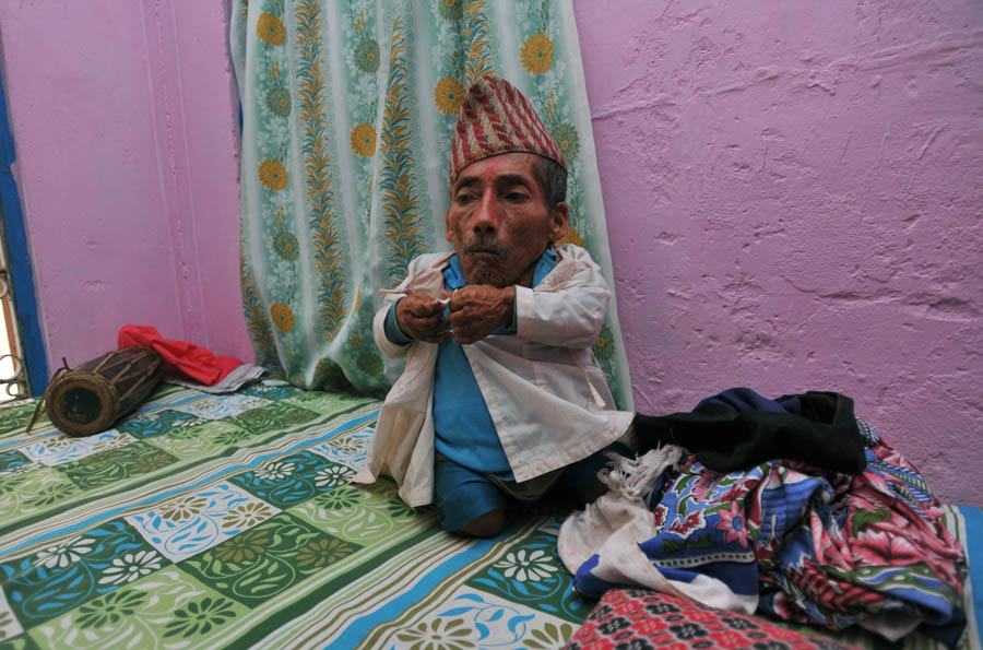 In a picture taken on February 7, 2012, Chandra Bahadur Dangi, a 72-year-old Nepali who claims to be the world's shortest man at 56 centimetres (22 inches) in height, puts on a shirt in Jhapa district, southeastern Nepal. Pilloried by neighbours, laughed at in freakshows and spurned by the women he admired from afar, Chandra Bahadur Dangi has always seen his tiny stature as a curse. But the 72-year-old Nepali, who claims to stand at just 56 centimetres (22 inches), is on the brink of life change as significant as a lottery win as experts prepare to test his claim to be the shortest man in history. AFP PHOTO/Prakash MATHEMA