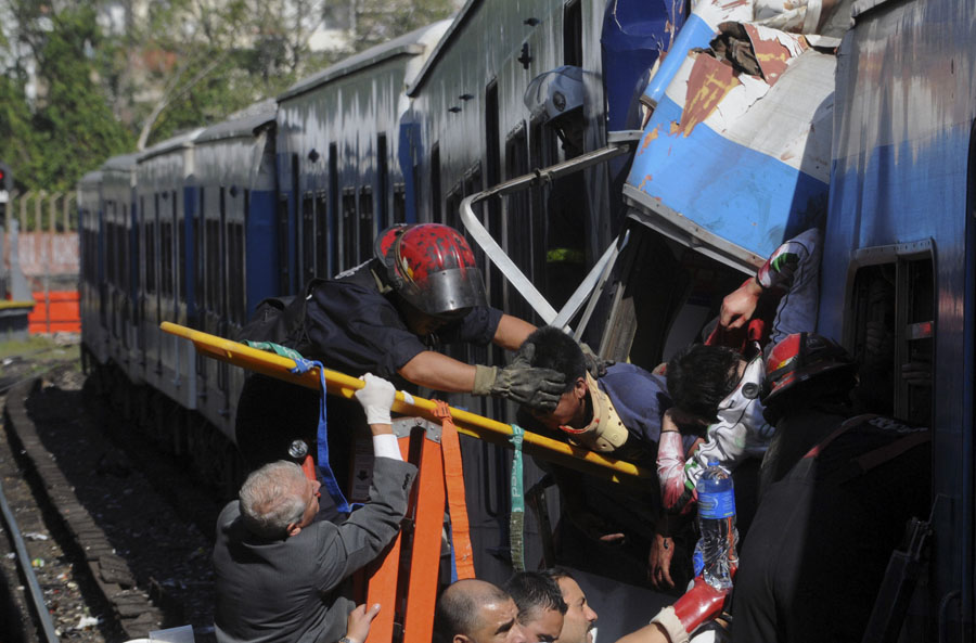 Firemen rescue wounded passengers from a commuter train after a collision in Buenos Aires, Argentina, Wednesday Feb. 22, 2012.  A packed train slammed into the end of the line in Buenos Aires' busy Once station Wednesday, injuring over 300 morning commuters, Argentina's transportation secretary said. (AP Photo/Leonardo Zavattaro,Telam)