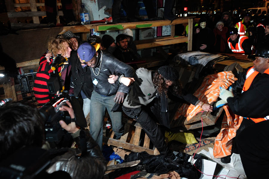 Protesters stand in front of a makeshift barricade at the Occupy protest camp outside Saint Paul's Cathedral in central London, early on February 28, 2012, as police and bailiffs move in to evict demonstrators. Police and bailiffs moved to dismantle the anti-capitalist camp which sprang up outside London's St Paul's Cathedral in October last year, according to the City's local authority.       AFP PHOTO/CARL COURT