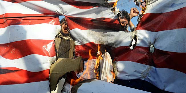 Pakistani Shiite Muslims shout slogans behind a burning US flag during a protest in Lahore on March 2, 2012, against the killing of Shia travellers in the Kohistan area. Sectarian gunmen disguised in military fatigues hauled 18 Shiite Muslim men off buses on February 28 and shot them dead in cold blood in a usually quiet region of northern Pakistan. Authorities blamed the assault on Islamist militant groups, without naming a specific organisation. The attack took place in the northern district of Kohistan, which neighbours the Swat valley, a former Taliban stronghold.   AFP PHOTO / ARIF ALI