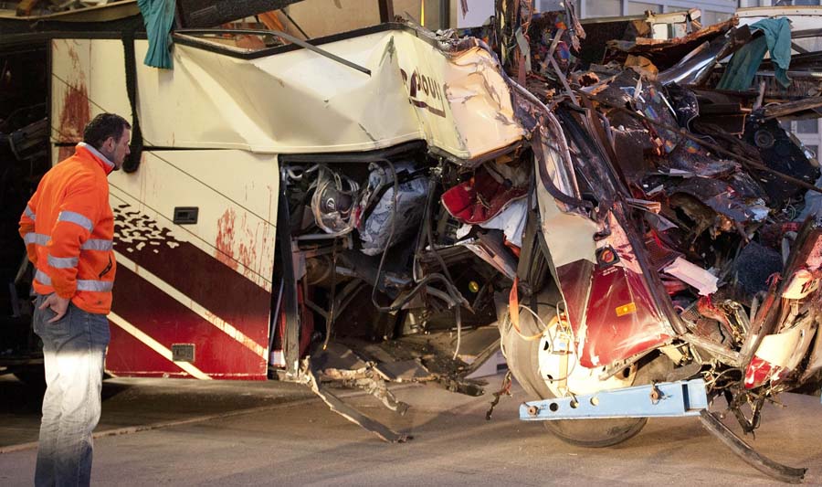 A rescue worker looks at blood stains on the wreckage of a tourist bus from Belgium as it is dragged by a tow truck outside the tunnel of the motorway A9, in Sierre, western Switzerland, early Wednesday, March 14, 2012. 28 people were killed in the bus crash. (AP Photo/Keystone, Laurent Gillieron)