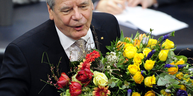 German new President Joachim Gauck holds flowers after being elected by the Bundesversammlung federal assembly at the Bundestag (lower house of parliament) on March 18, 2012 in Berlin. Gauck, a 72-year-old Lutheran pastor from the former East Germany, has been elected in with cross-party support by this special body made up of MPs and other dignitaries.  AFP PHOTO / JOHN MACDOUGALL