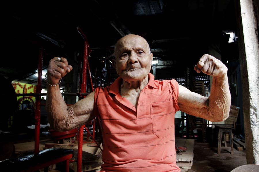 In this Friday, March 16, 2012 photo, Indian body builder Manohar Aich flexes his muscles as he poses for a photograph in a gymnasium in Kolkata, India. Aich, who is only 4 foot 11 inches (150 centimeters) tall, won the Mr. Universe title in London way back in 1952. Happiness and a life without tensions are the key to his longevity, said Aich, who turned 100 on March 17. (AP Photo/Bikas Das)