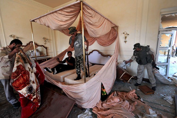 Libyan National Transitional Council (NTC) fighters search a room at ousted Libyan leader Moamer Kadhafi's Sirte palace, partly destroyed by NATO air raids according to fighters, on October 9, 2011. Forces of Libya's new regime were on the verge of claiming full control of Moamer Kadhafi's hometown Sirte after seizing its showpiece conference centre and university from his diehards. AFP PHOTO/ARIS MESSINIS
