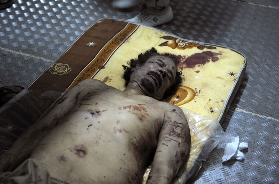 The body of ousted Libyan strongman Moamer Kadhafi lies on a mattress in the cold storage room of a vegetable market near a mosque in the outskirts of Misrata on October 21, 2011. Libya's leaders faced huge pressure to proclaim the country's liberation and move toward democracy, amid euphoria over the killing of Kadhafi under still murky circumstances. AFP PHOTO/PHILIPPE DESMAZES