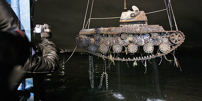 In this photo taken on late Wednesday, Nov. 16, 2011, a floating crane lifts from the Neva river a KV-1 tank which was found underwater near Kirovsk, 50 kilometers (31 miles) east of St. Petersburg, Russia. (AP Photo/Dmitry Lovetsky)