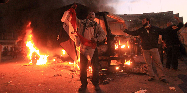 An Egyptian police vehicle burns as protesters chant during clashes with riot police at Cairo's landmark Tahrir Square on November 19, 2011. Egyptian police fired rubber bullets and tear gas to break up a sit-in among whose organisers were people injured during the Arab Spring which overthrew veteran president Hosni Mubarak.   AFP PHOTO / KHALED DESOUKI