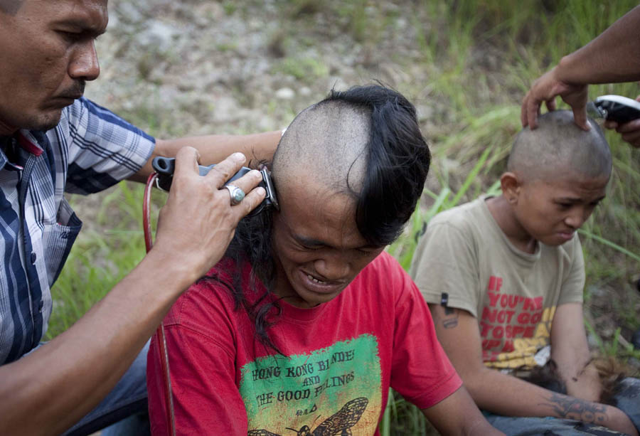 In this photograph taken on December 13, 2011 police shave the hair of detained Indonesian punks at a police school in Aceh Besar in Aceh province. Sharia police are 