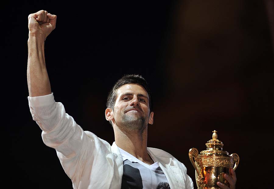 Serbian tennis player Novak Djokovic reacts as he displays his Wimbledon trophy to his fans during a welcoming ceremony in front of the Serbian National Assembly in Belgrade on July 4, 2011. Tens of thousands of people gathered in front of the Serbian parliament today to greet Novak Djokovic after he won his first Wimbledon crown and became the world's new number one.   AFP PHOTO/ ANDREJ ISAKOVIC