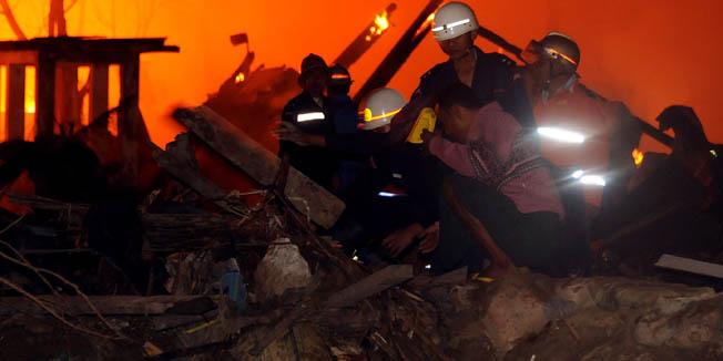 Myanmar rescue workers search for bodies from a large unexplained explosion and fire in Yangon on December 29, 2011. At least 15 people were killed and dozens more injured in anexplosion and fire in Myanmar's commercial hub and former capital Yangon early on Thursday, officials and witnesses said. AFP PHOTO/Soe Than WIN