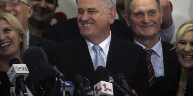 Tomislav Nikolic, center, the nationalist Serbian Progressive Party leader and presidential candidate, smiles as he talks to members of the media after claiming victory at the presidential runoff elections in Belgrade, Serbia, Sunday, May 20, 2012, with his wife, Dragica at left.  Nationalist Nikolic beat pro European Union incumbent Boris Tadic in Serbia's presidential runoff election. (AP Photo/ Marko Drobnjakovic)