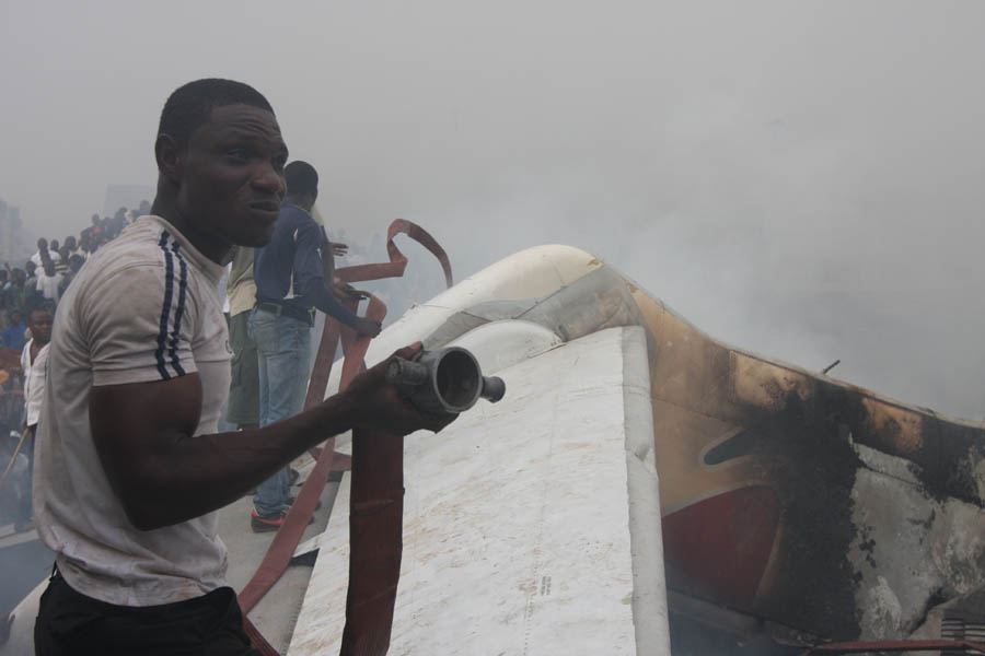 Onlookers stand on the tail wing of a crashed passenger plane in a neighborhood just north of Murtala Muhammed International Airport, in Lagos, Nigeria, Sunday, June 3, 2012. The passenger plane carrying more than 150 people crashed in Nigeria's largest city on Sunday, government officials said. The Lagos state government said in a statement that 153 people were on the Dana Air flight Sunday. (AP Photo/Jon Gambrell)