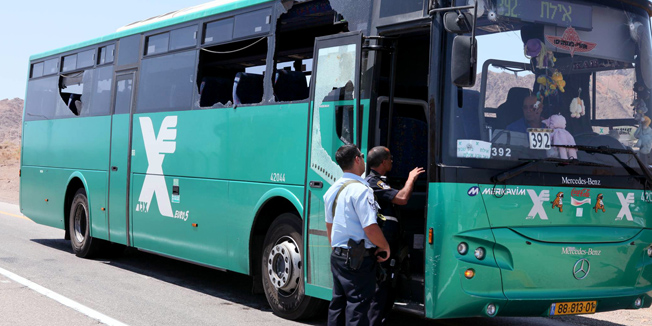 Israeli policemen talk to a driver sitting in a bus that was ambushed on route 12 about 20 km north of the Red Sea resort of Eilat as it was traveling near the border with Egypt on August 18, 201. At least five people were killed and more than 25 hurt in three attacks in southern Israel, including a shooting ambush, and IED and RPG attack, Israeli medics and the army said. AFP PHOTO/YEHUDA BEN ITAH           ISRAEL OUT