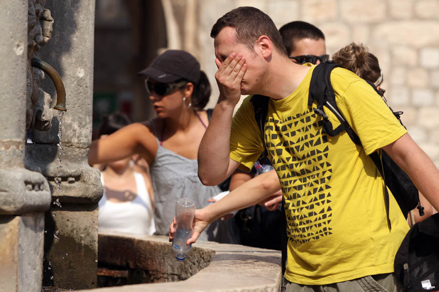Dubrovnik, 290811.I danas mogobrojni turisti na Stradunu traze osvjezenje od vrucine na Velikoj i Maloj Onofrijevoj fontani, ispijaju vece kolicine vode, jedu sladolede i koriste kisobrane.Foto: Zoran Kusalo / CROPIX