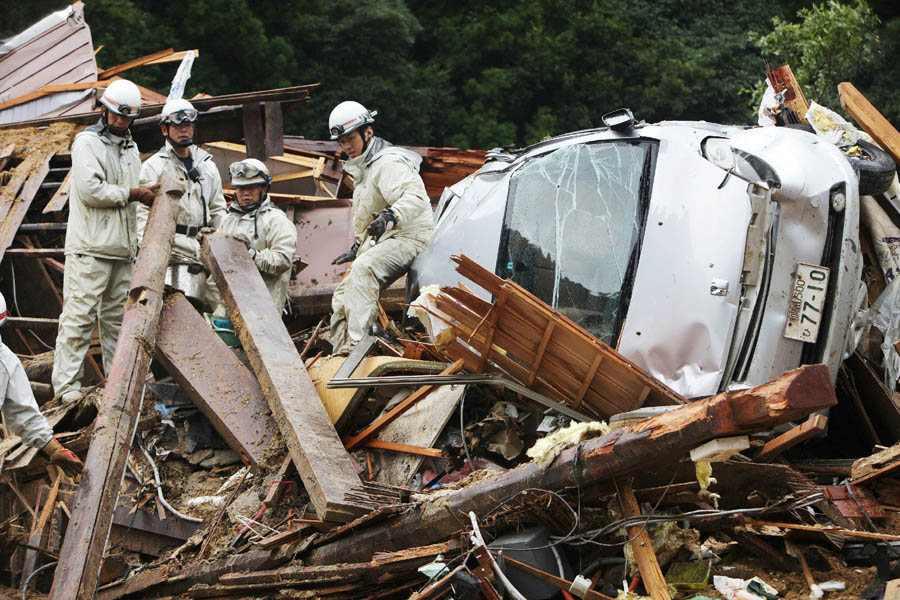 Rescue workers search for missing people amongst a destroyed house caused by floodwaters in Tanabe, Wakayama prefecture, in western Japan on September 4, 2011. Typhoon Talas cut across western Japan late on September 3, leaving at least 17 people dead and 43 missing after heavy rains and fierce winds.  AFP PHOTO / JIJI PRESS