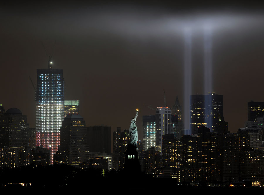 The annual Tribute in Light memorial that echos the shape of New York's World Trade Center twin towers is illuminated with the  Statue of Liberty (C) and 1 World Trade Center (L) during the 10th Anniversary of the September 11, 2001 attacks at the lower Manhattan site of the World Trade Center September 11, 2011 in this view from Bayonne, New Jersey. AFP PHOTO/Stan HONDA