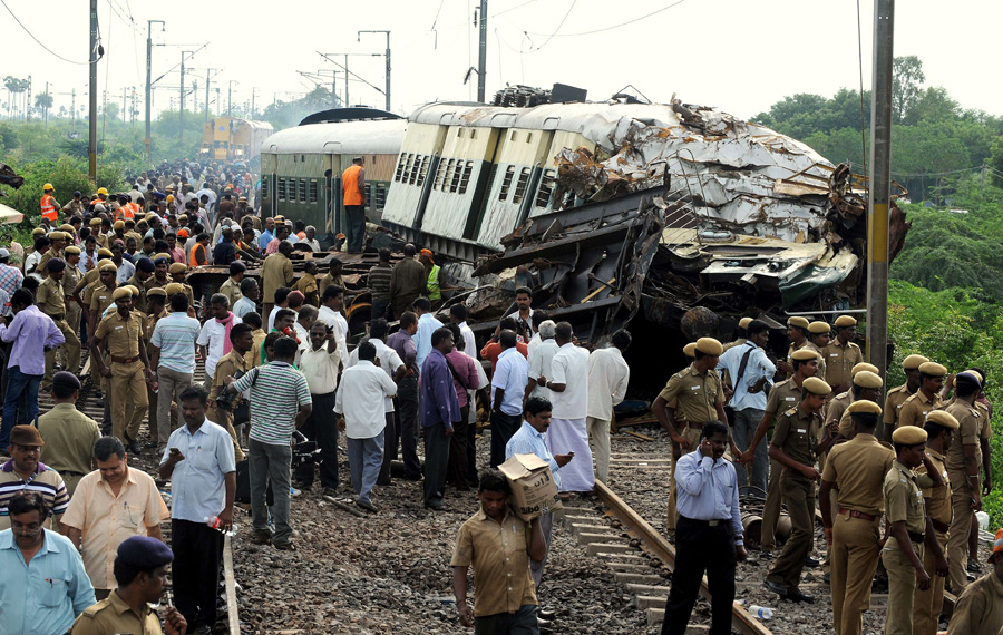 Indian Railway officials, security personnel and onlookers gather around the wreckage of train carriages at Arakkonam, some 55 miles (90 kilometres) west of Chennai on September 14, 2011, after a crash between two trains in the southern Indian state of Tamil Nadu. Indian railway officials have blamed driver error for a late-night collision between two passenger trains that killed nine people and injured more than 80.  Emergency teams worked to clear the crash site, where five coaches were derailed in the impact. Southern Railway general manager Deepak Krishnan said initial investigations suggested the driver of the moving train, who survived the crash, had ignored speed restrictions and signal lights.   AFP PHOTO/Manjunath KIRAN