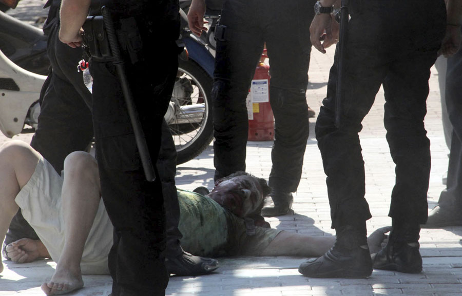 A man lies down surrounded by police officers after setting himself on fire outside a branch of Piraeus bank in the northern port city of Thessaloniki, Greece, Friday Sept. 16, 2011. It was a third attempted self-immolation by the former small business owner, who says he was ruined after taking a series of bank loans. The 56-year-old was hospitalized with non life-threatening chest burns. (AP Photo/Nontas Stlianidis)